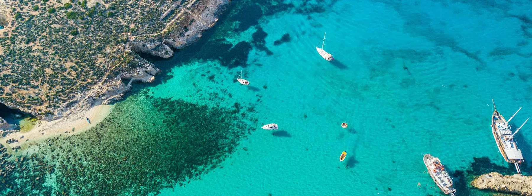 Blue Lagoon Comino Malta with turquoise water, white sand, and swimmers enjoying crystal clear sea from a private boat