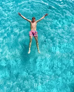 Person floating in crystal clear blue waters at the Blue Lagoon Comino, enjoying calm sea during a private boat trip in Malta.