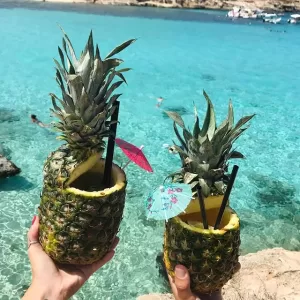 Pineapple floating in bright turquoise blue waters around Comino, Malta.