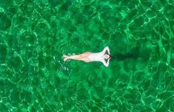 Lady floating in Crystal Lagoon Malta clear blue water during private boat tour Comino swimming away from crowds in turquoise sea