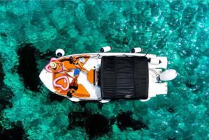 Drone shot of a private boat floating in the bright turquoise waters of the Blue Lagoon in Comino, Malta.