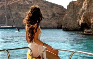 Guests enjoying Malta’s clear blue waters while swimming and relaxing near a boat during a private boat trip.