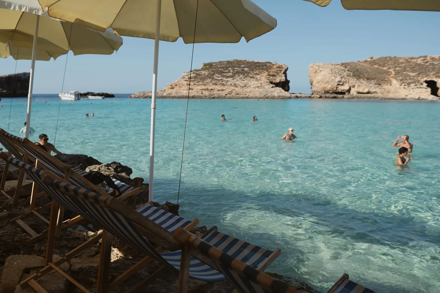 Blue Lagoon Comino Malta with white umbrellas and clear blue water, showing a quiet moment without crowds on a sunny day.