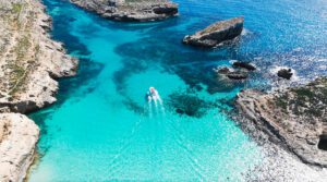 Private boat charter passing through the Blue Lagoon Malta, surrounded by crystal clear turquoise waters near Comino Island.