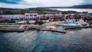 Comino Hotel building overlooking the turquoise sea and Santa Marija Bay on Comino Island, Malta.