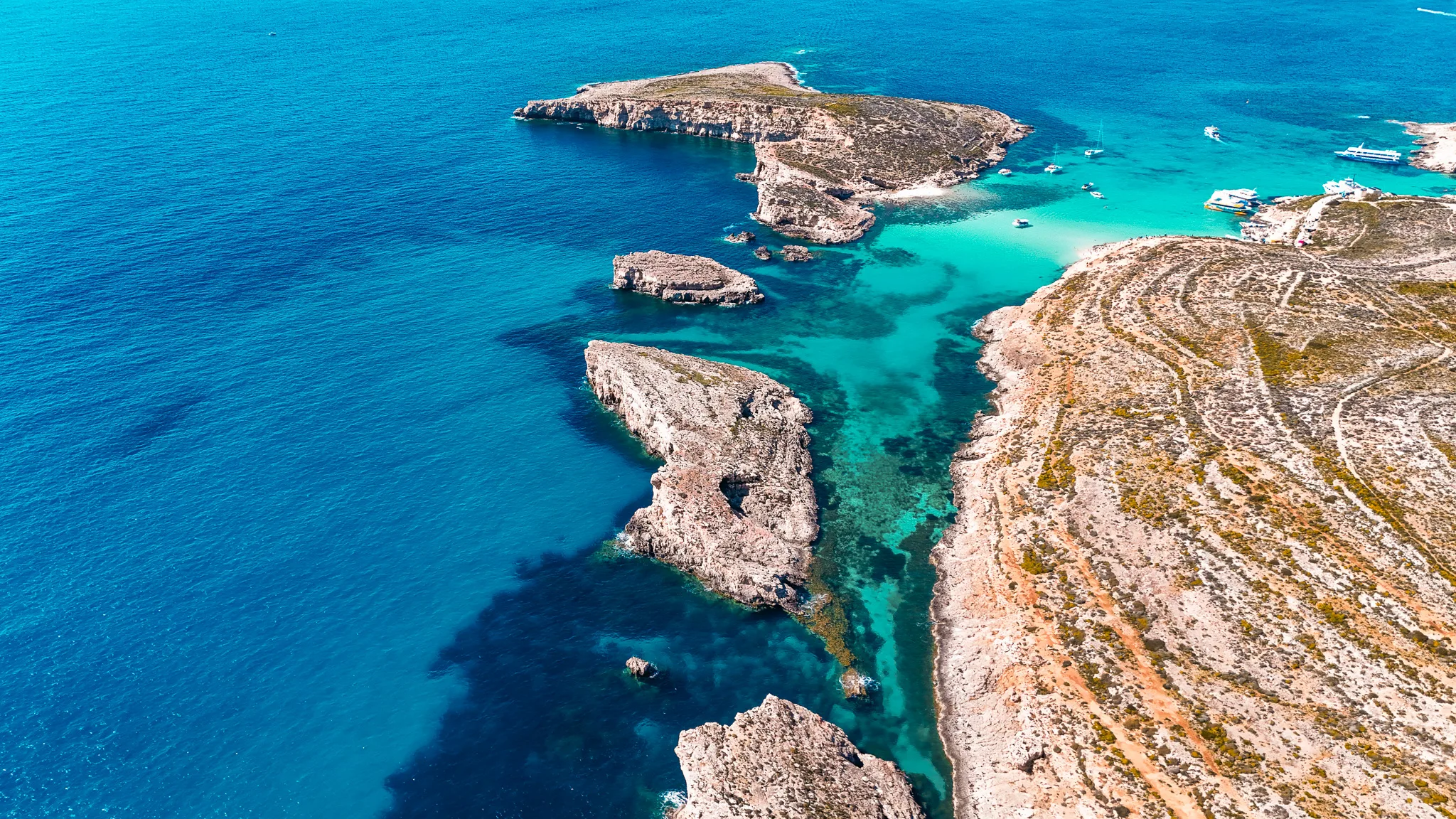 Comino Island and surrounding islets in Malta, showing rugged coastline and clear blue waters viewed from a private boat.