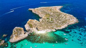 ominotto Island near Comino showing clear turquoise waters and rocky shoreline, a quiet swimming spot best reached by private boat in Malta.
