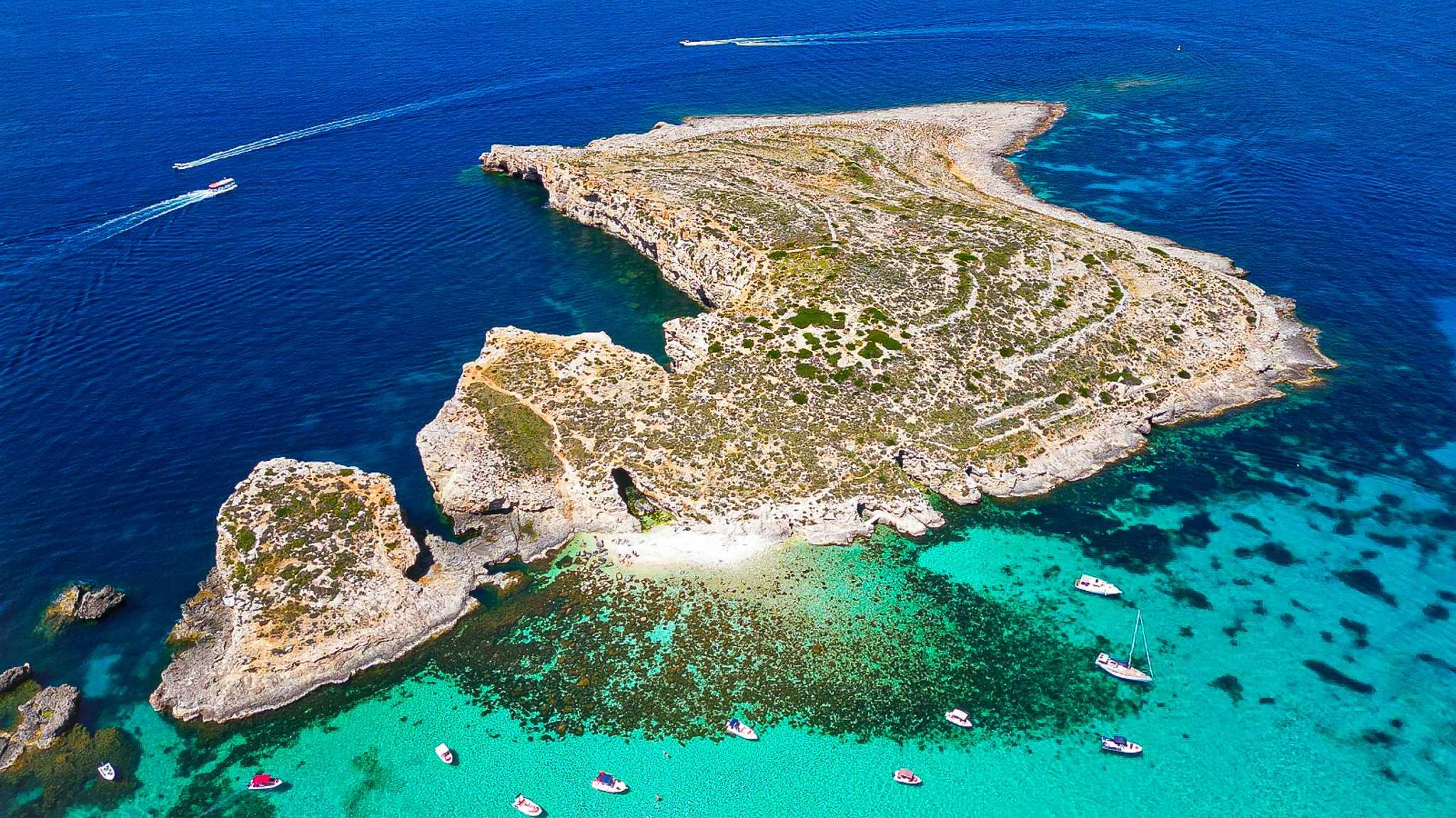 ominotto Island near Comino showing clear turquoise waters and rocky shoreline, a quiet swimming spot best reached by private boat in Malta.