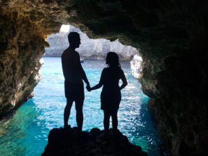 Happy couple inside a sea cave during a boat tour in Malta, enjoying clear water and a private boating experience.