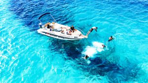 Guest jumping from the front boat platform into the Blue Lagoon Malta, surrounded by clear turquoise water near Comino Island.