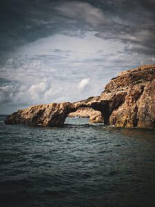 Kissing Elephant Rock in Comino Malta, a natural rock formation shaped like two elephants touching trunks above the clear turquoise sea.