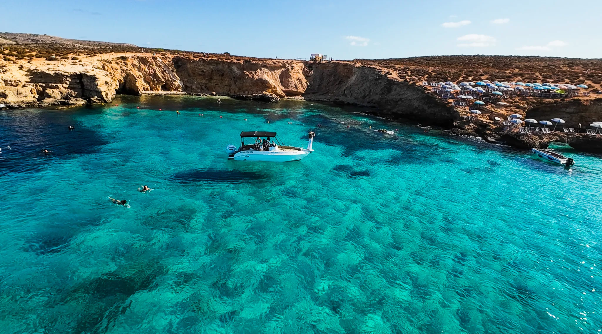 Woman relaxing on a boat at the Blue Lagoon Malta, surrounded by clear turquoise water near Comino Island.
