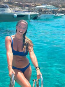 Guest climbing the swim stairs from the Blue Lagoon Malta, with clear turquoise water and a private boat nearby.