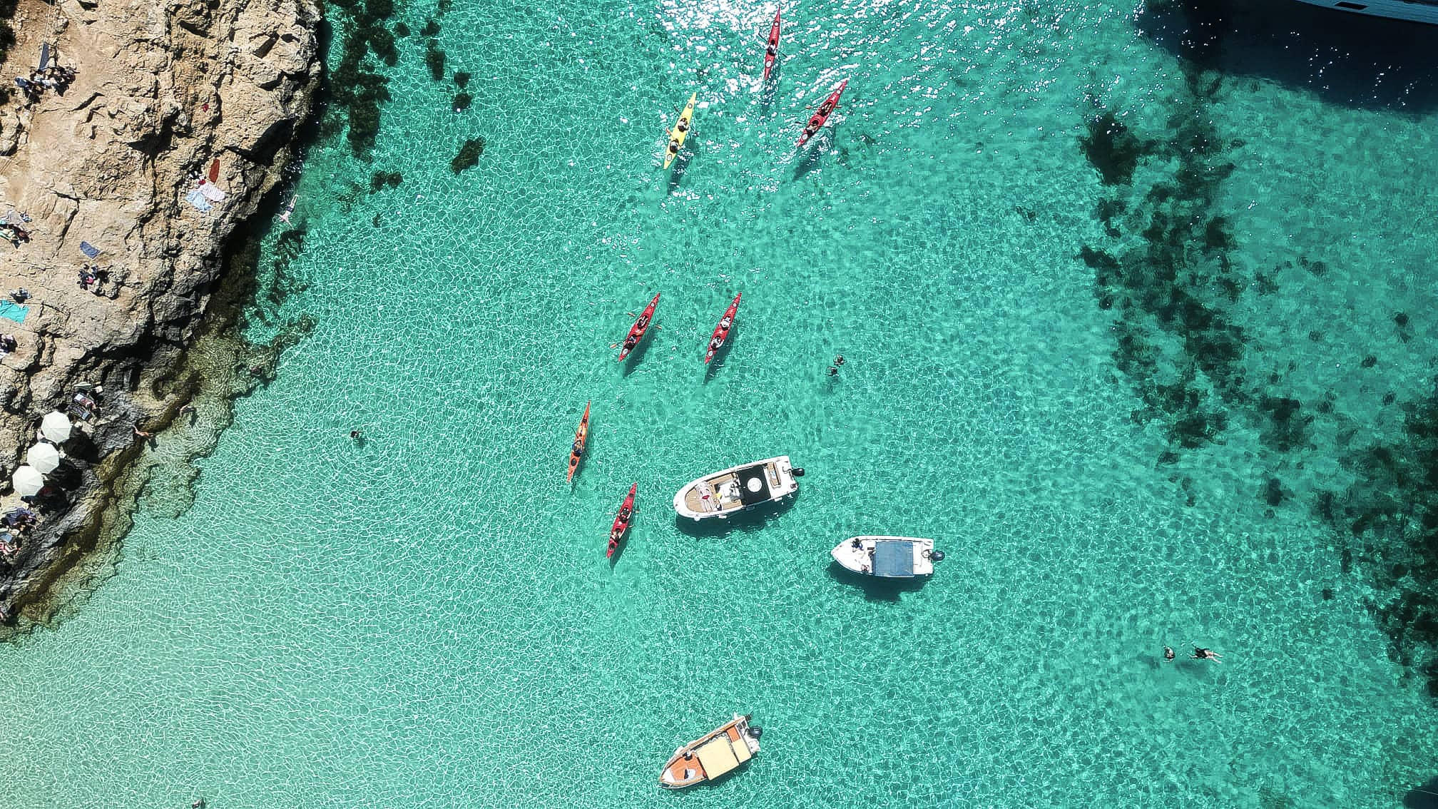 Kayak and small boat floating in the bright blue waters of the Blue Lagoon in Comino, Malta.