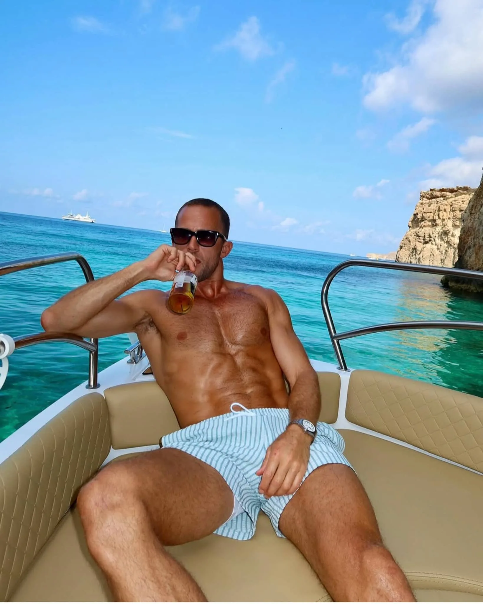 Man posing for an Instagram-style photo on a private boat in Malta with bright turquoise water around Comino.