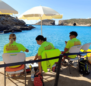 Lifeguards watching over swimmers in the bright turquoise waters of the Blue Lagoon in Comino, Malta.
