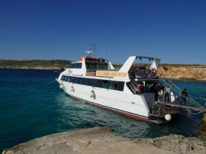 Crowded shared boat tour in Malta with many passengers visiting the Blue Lagoon in Comino.