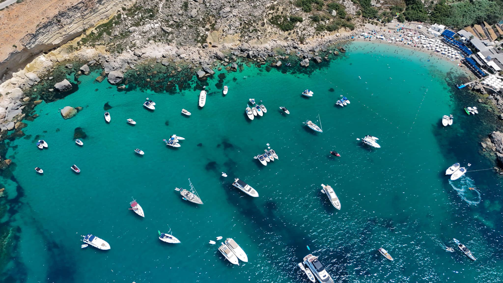 Boats floating in the crystal-clear water of Paradise Bay, Malta